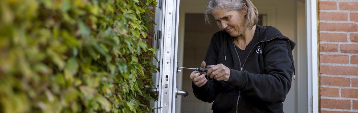 CERTEGO-tekniker arbetar med låset på en ytterdörr till en fastighet.