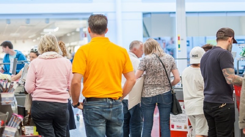 Several people standing in line in a grocery store.