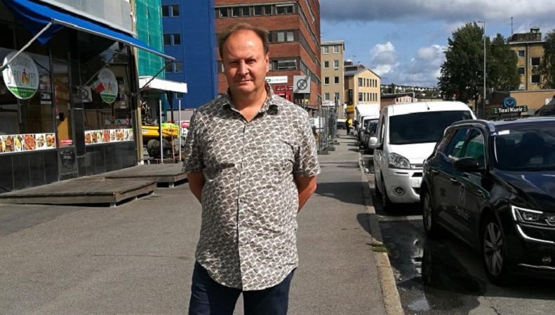 Mario Cerutti in front of a street full of parked cars.